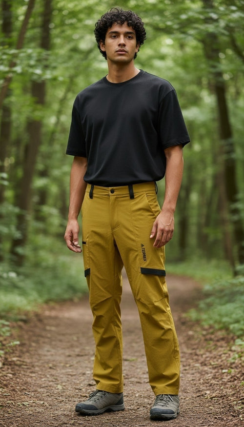 Off The Rails IOM men's mustard yellow Adidas Terrex Zupahike hiking pants with cargo pockets worn in a forest.